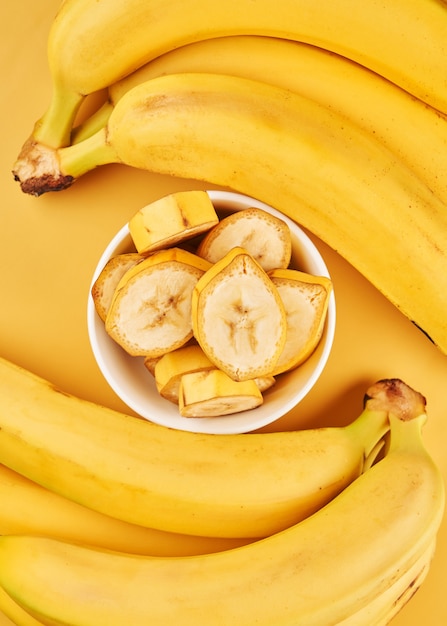 Biały Kubek Z Pokrojonymi Bananami Na żółtym Tle. Owoce Tropikalne, Zdrowa żywność, Witaminy