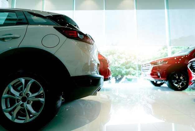 Biały luksusowy samochód SUV zaparkowany w nowoczesnym salonie i zamazany czerwony samochód Salon samochodowy i leasing samochodów