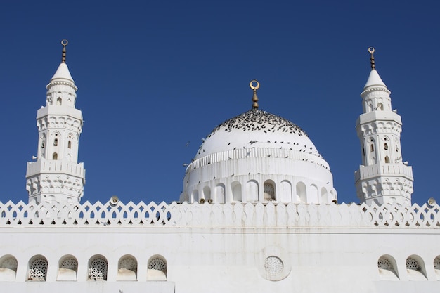 Biały meczet ze złotą i białą kopułą i złotym wzorem.