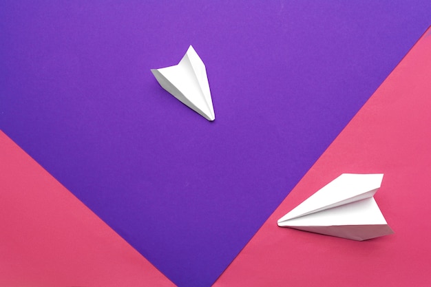 biały papierowy samolot na kolorowym papierze blokowym