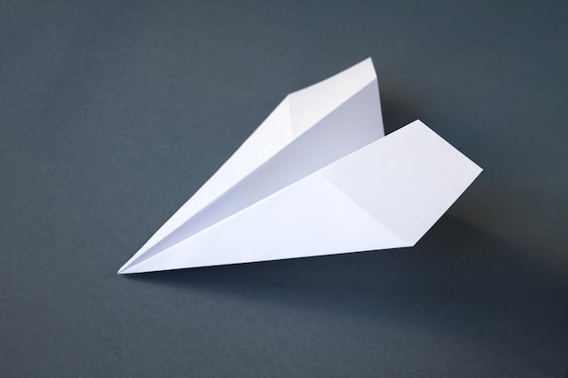 Biały papierowy samolot origami na białym tle na szarym tle