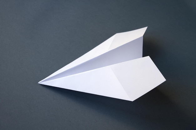 Biały papierowy samolot origami na białym tle na szarym tle