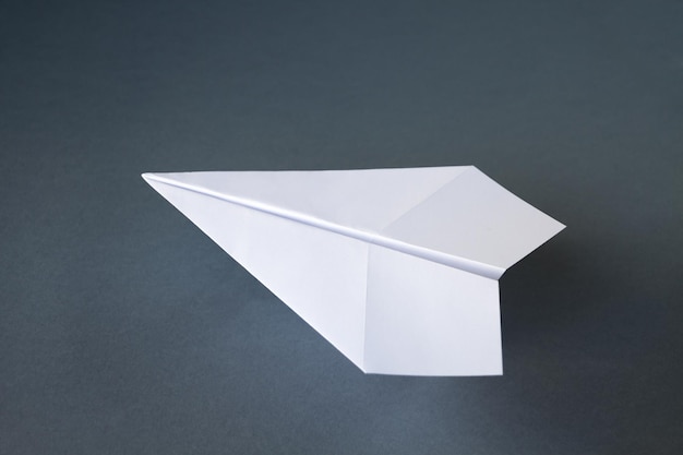 Biały papierowy samolot origami na białym tle na szarym tle