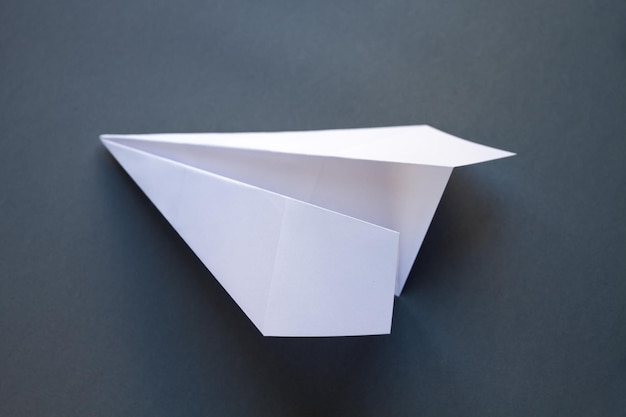 Biały papierowy samolot origami na białym tle na szarym tle