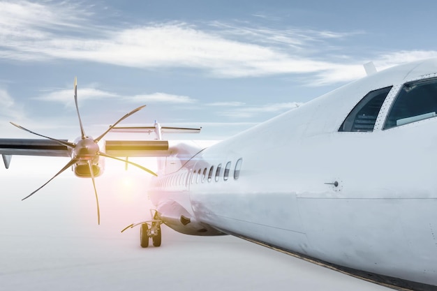 Biały pasażerski samolot turbośmigłowy na białym tle na jasnym tle z niebem