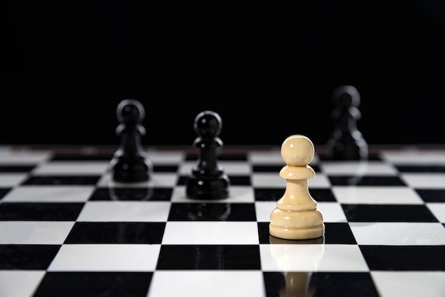Biały pionek stoi na szachownicy na czarno