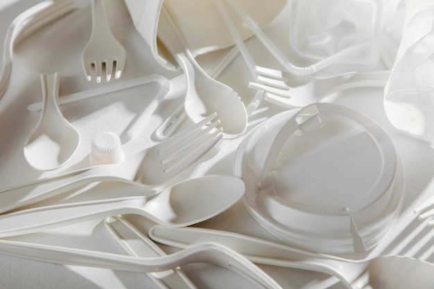 Biały plastik jednorazowego użytku na białym tle. Zbliżenie. Pojęcie recyklingu tworzyw sztucznych i ekologii. Płaski układanie, widok z góry