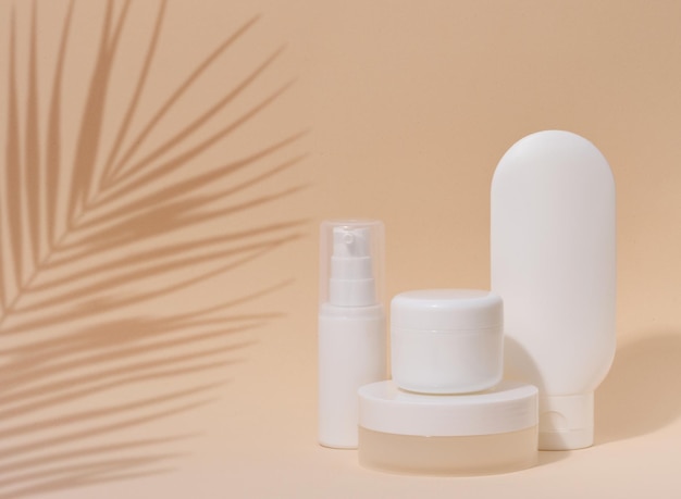 Biały plastikowy pojemnik tuba słoik z pokrywką na kosmetyki na beżowym tle z cieniem z liścia palmowego Reklama i promocja