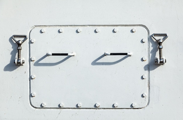 Zdjęcie biały prostokątny właz na kadłubie statku jest zamknięty i zaryglowany