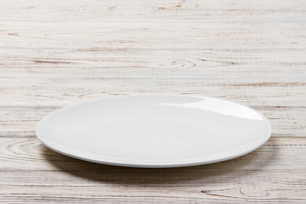 Biały Round talerz na białym drewnianym stołowym tle. Widok perspektywiczny