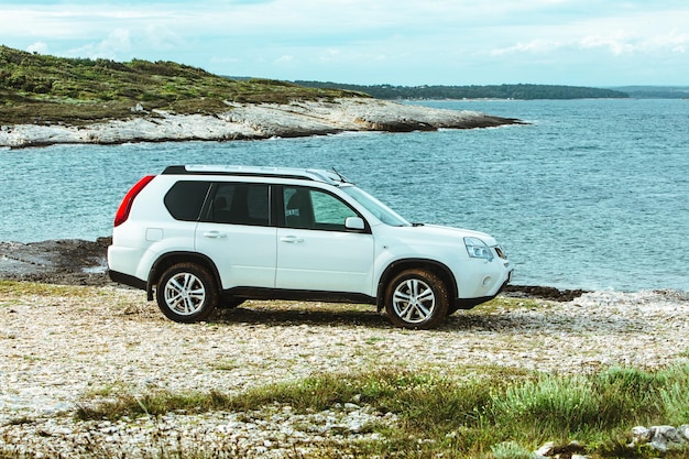 Biały samochód suv na skalistym wybrzeżu poza koncepcją podróży samochodem drogowym