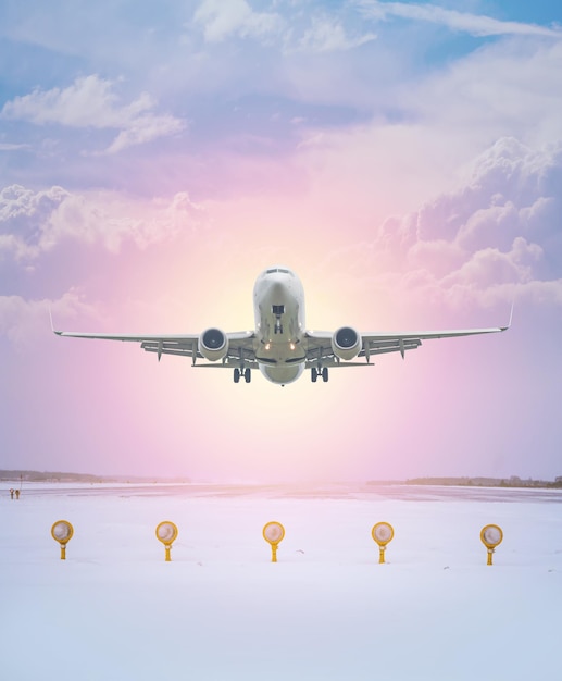 Biały samolot pasażerski startuje z zimowego pasa startowego lotniska na tle porannego nieba