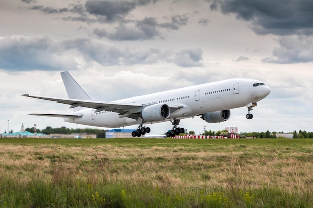 Biały szerokokadłubowy samolot pasażerski w powietrzu podczas startu przy pochmurnej pogodzie