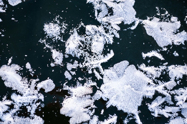 Biały szron na powierzchni lodu na jeziorze. Obraz makro. Piękne zimowe tło przyrody