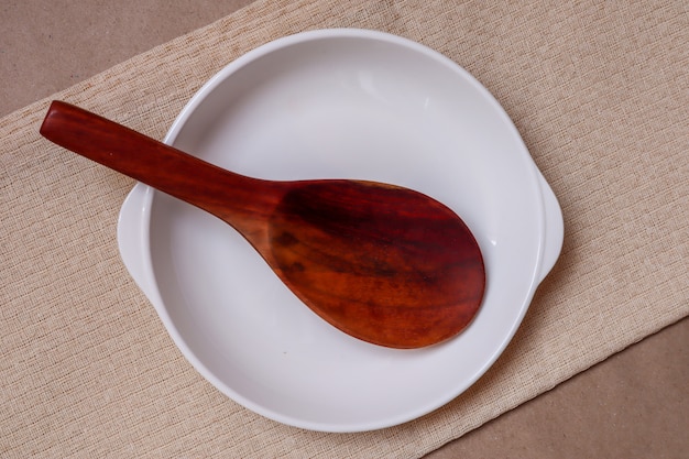 Zdjęcie biały talerz i drewniana łyżka na kremowym obrusie gotowym do spożycia