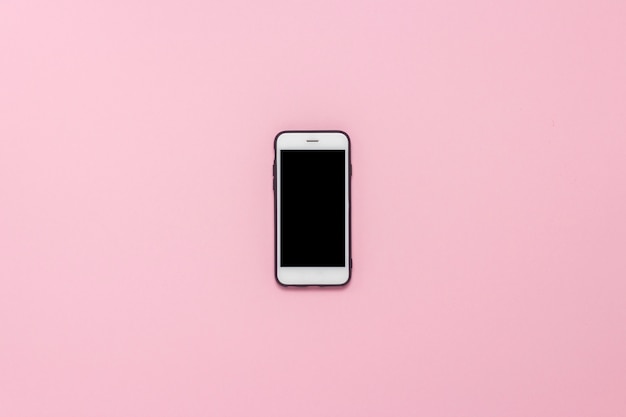 Biały telefon komórkowy w czarnej skrzynce na odosobnionym różowym tle. Leżał płasko, widok z góry.