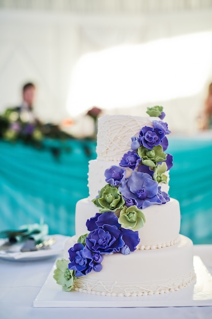 Biały tort weselny ozdobiony niebieskimi kwiatami