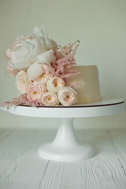 Zdjęcie biały tort weselny ozdobiony świeżymi różami, piwoniami i zielenią