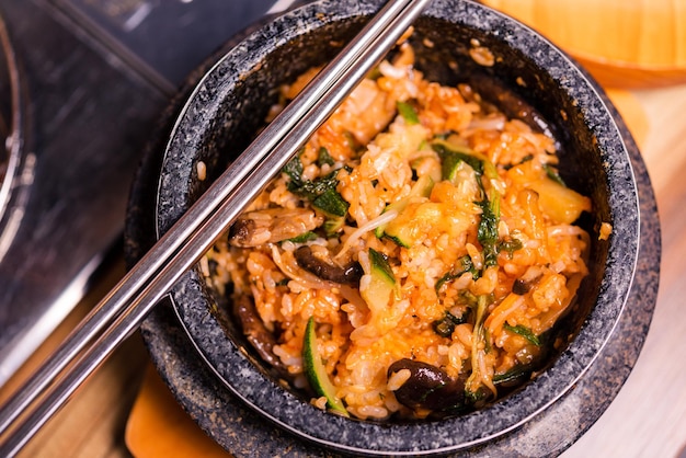Zdjęcie bibimbap w czarnej podgrzewanej kamiennej misce koreańskie tradycyjne danie bibimbap mieszany ryż z warzywami