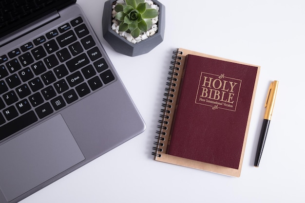 Biblia i laptop na widoku z góry stołu roboczego. Studium biblijne online