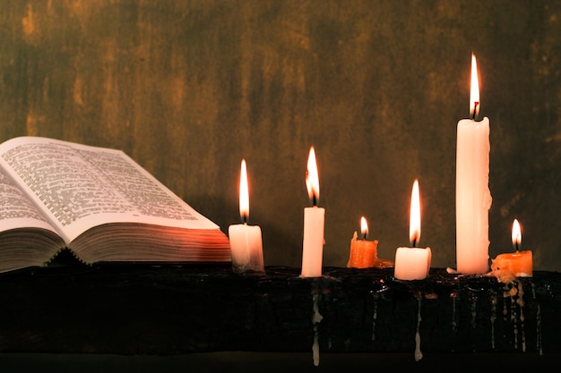 Biblia i świeca na starym drewnianym stole. Piękne złote tło. Koncepcja religijna.