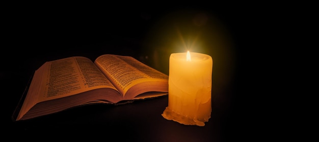 Biblia na stole w świetle świecy