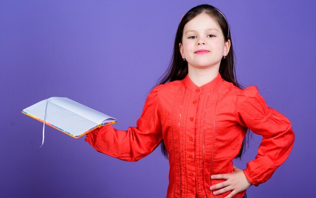 Biblioteka jest świątynią nauki Pewne siebie małe dziecko trzymające książkę biblioteczną Urocza mała lektorka z otwartą książką Czytanie w szkolnej bibliotece