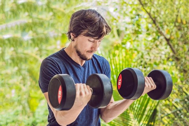 Biceps curl - trening siłowy fitness mężczyzna poza ćwiczeniem ramion podnoszenia hantli robi loki na biceps. Męski model sportowy, ćwiczenia na świeżym powietrzu w ramach zdrowego stylu życia.