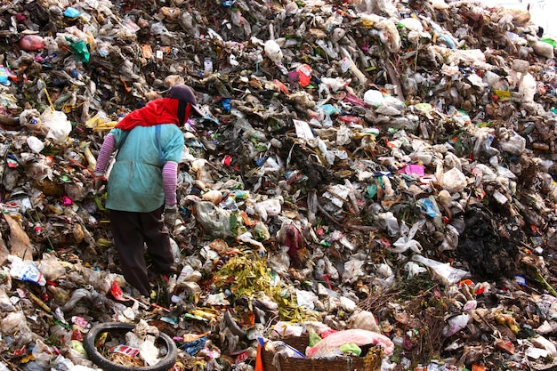 Biedni ludzie znajdują lub przeszukują śmieci do sprzedaży w celu ponownego wykorzystania i recyklingu na wysypisku