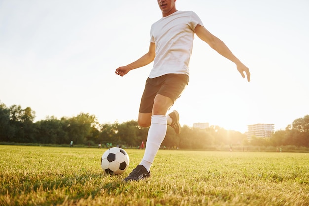 Biega z piłką Młody piłkarz trenuje na boisku sportowym