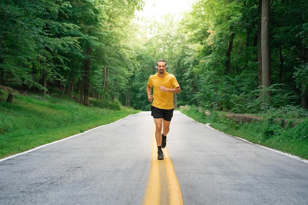 Biegacz człowiek jogging na ścieżce w mieście. Sportowiec w średnim wieku działa słuchanie muzyki na słuchawkach.