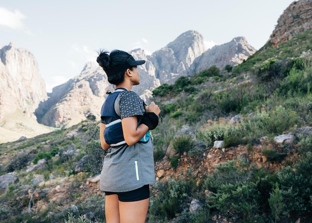 Biegacz w stroju sportowym stojący w dolinie Młoda kobieta w stroju fitness w dzikim terenie