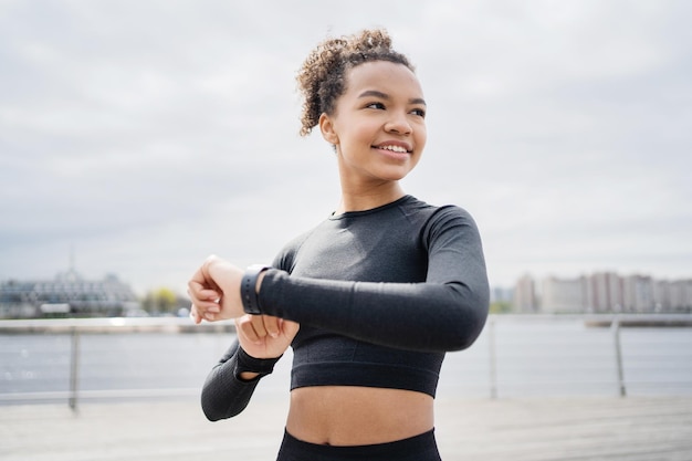 Biegaczka używa zegarka fitness do treningu, trener jest ubrany w dres