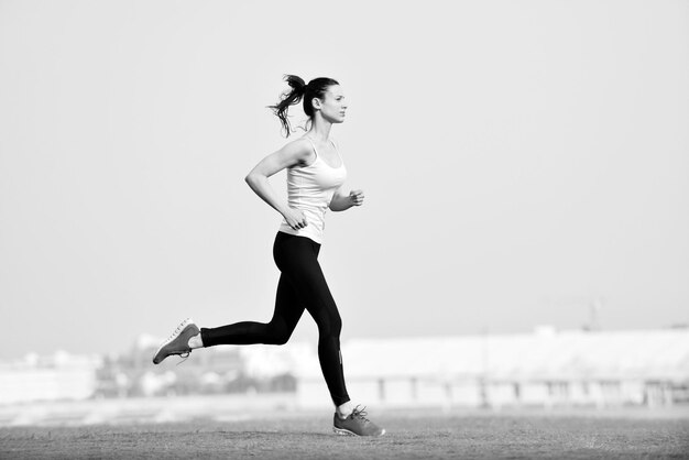 Bieganie w parku miejskim. Kobieta biegacz na zewnątrz jogging rano z miejską sceną Dubaju w tle