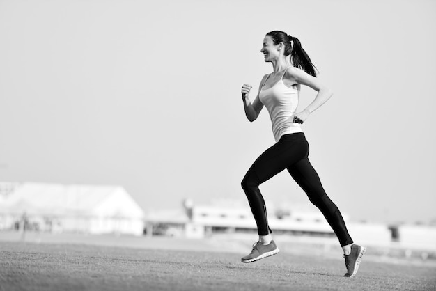 Bieganie w parku miejskim. Kobieta biegacz na zewnątrz jogging rano z miejską sceną Dubaju w tle