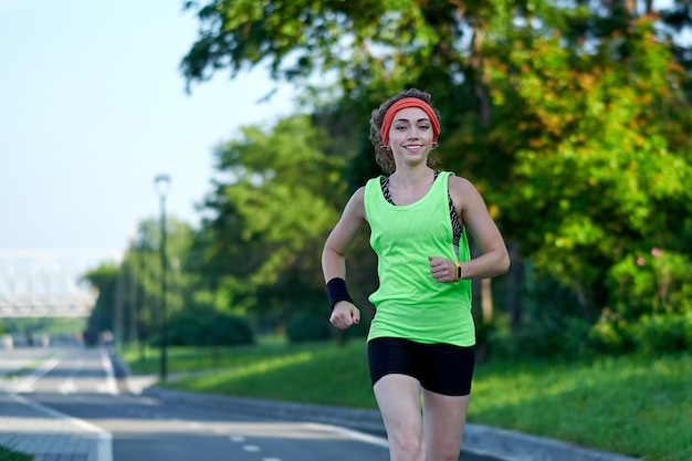 Biegnąca kobieta Kobieta biegaczka Jogging podczas treningu na świeżym powietrzu w parku Piękna szczupła dziewczyna Modelka fitness na zewnątrz Odchudzanie