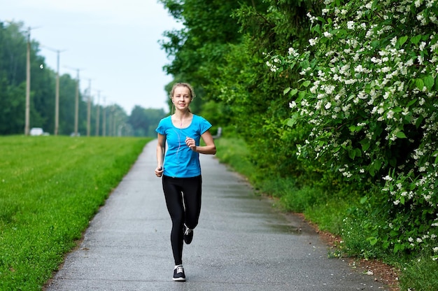 Biegnąca kobieta sportowiec spotman trening w letnim parku Portret fitness na świeżym powietrzu