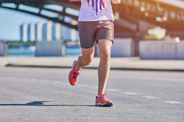 Biegnący mężczyzna. Lekkoatletycznego mężczyzna joggingu w odzieży sportowej na drodze miasta