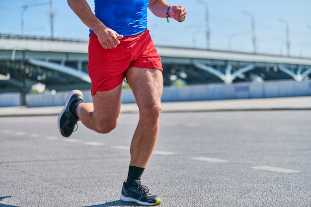 Biegnący Mężczyzna. Lekkoatletycznego Mężczyzna Joggingu W Odzieży Sportowej Na Drodze Miasta.