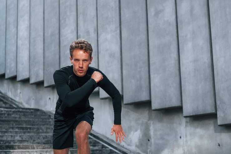 Zdjęcie biegnie do przodu młody mężczyzna w sportowym stroju ma trening na świeżym powietrzu w ciągu dnia
