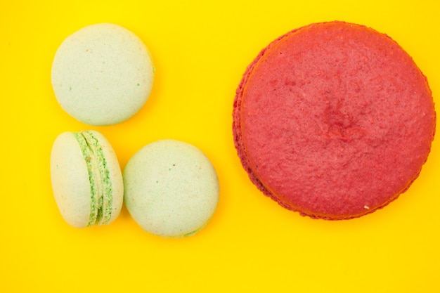 Big Sweet macaron macaron obok małych makaroników na żółtym tle. Luksusowy deser