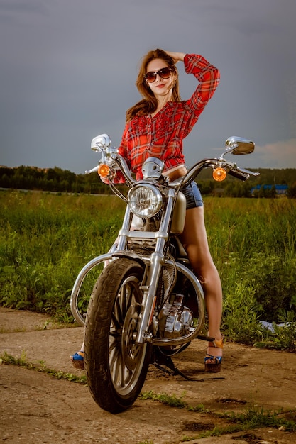 Biker dziewczyna z okularami przeciwsłonecznymi i motocyklem