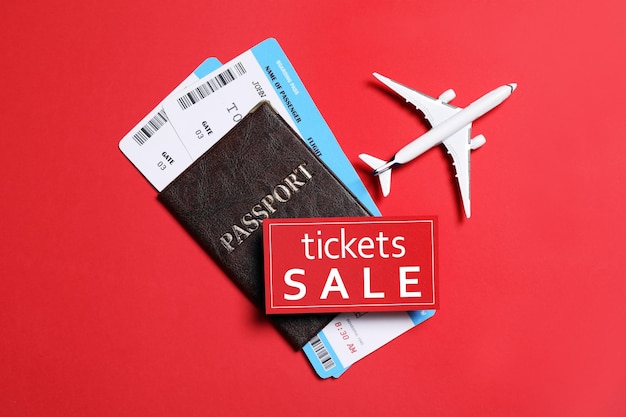 Bilety lotnicze model samolotu paszportowego i karta WYPRZEDAŻ na czerwonym tle leżał płasko
