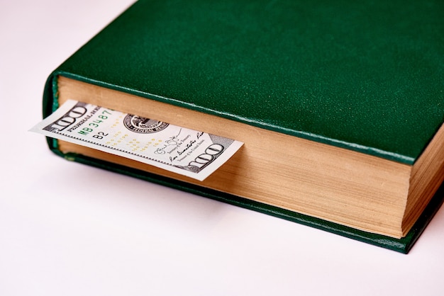 Bill wart sto dolarów amerykańskich w książce na białym tle makro.