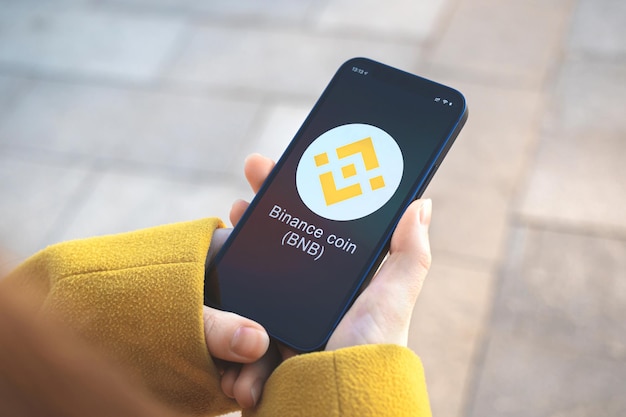 Binance Moneta Symbol Kryptowaluty Bnb, Logo. Koncepcja Biznesowa I Finansowa. Ręka Ze Smartfonem, Ekran Z Zbliżeniem Ikony Krypto