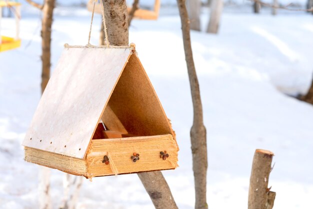 Birdhouse wiszące na drzewie na tle ogrodzenia i śniegu