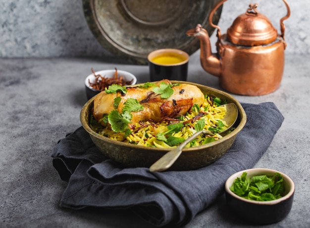 Biryani kurczak, tradycyjne danie kuchni indyjskiej, z ryżem basmati, smażoną cebulą, świeżą kolendrą w misce na szarym tle rustykalnym kamienia. Autentyczny indyjski posiłek, zbliżenie, selektywne skupienie