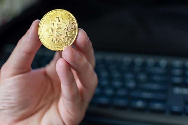 Bitcoin w ręku na tle klawiatury