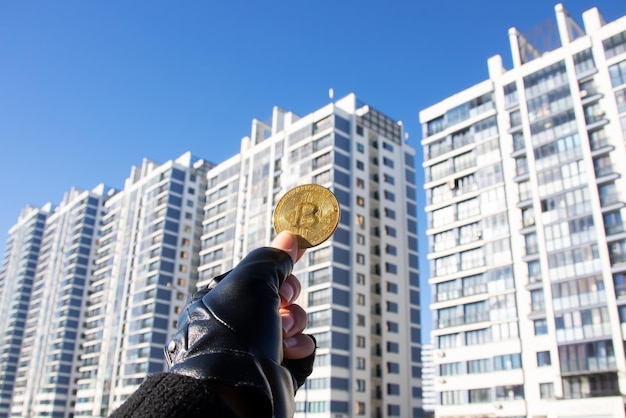 Bitcoin w ręku na tle wysokich nowoczesnych budynków