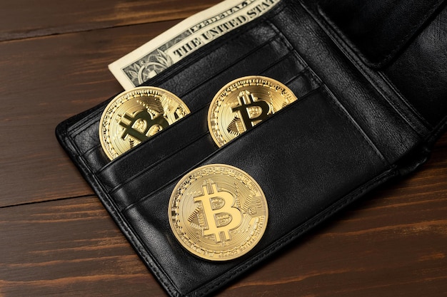 Bitcoinowe monety złota w czarnym portfelu na drewnianym stole